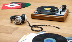 Retro styled Best portable turntable, vinyl LPs and a head set on a wooden surface