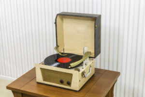 Vintage Best portable record player with vinyl album on wood table.